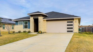 A residential house with a garage, a driveway, and a lawn. - Resort Perks & Private Yard: Brookshire Retreat (Katy)