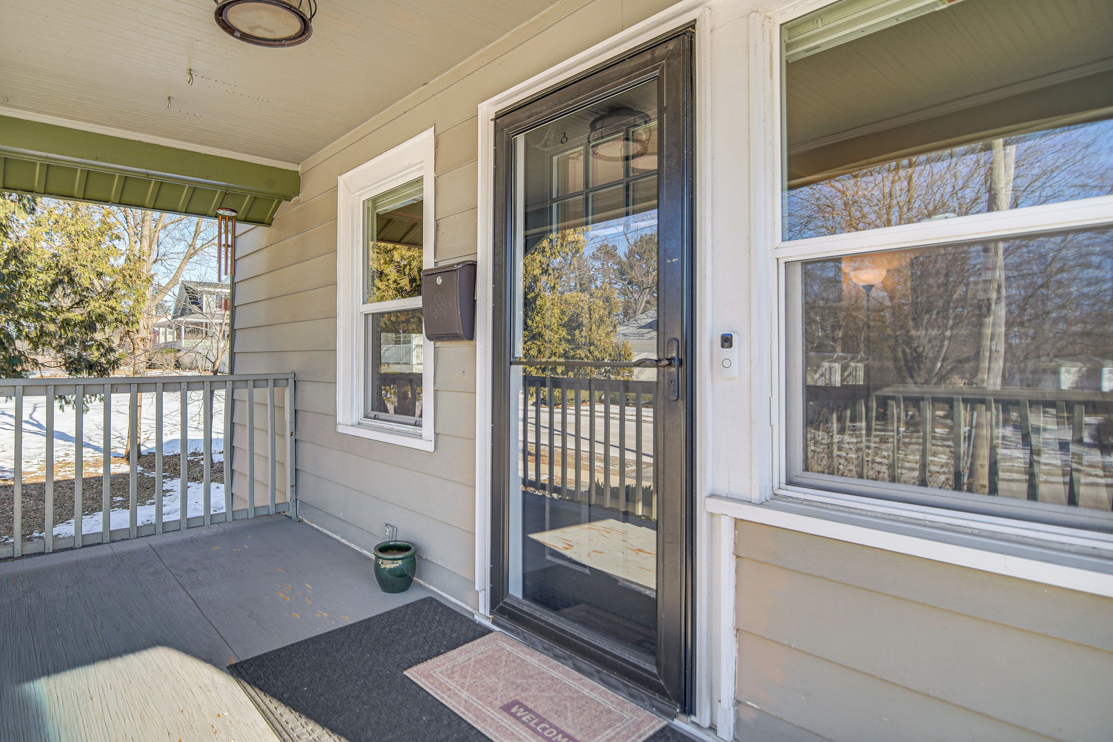 A front porch with a sliding glass door, a mailbox, and a welcome mat.