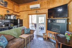 A cozy cabin interior with a wooden interior, a kitchenette, a comfortable seating area, and a flat-screen TV. - Private Hot Tub, Deck & Mtn Views! Hickman Retreat (Hickman)