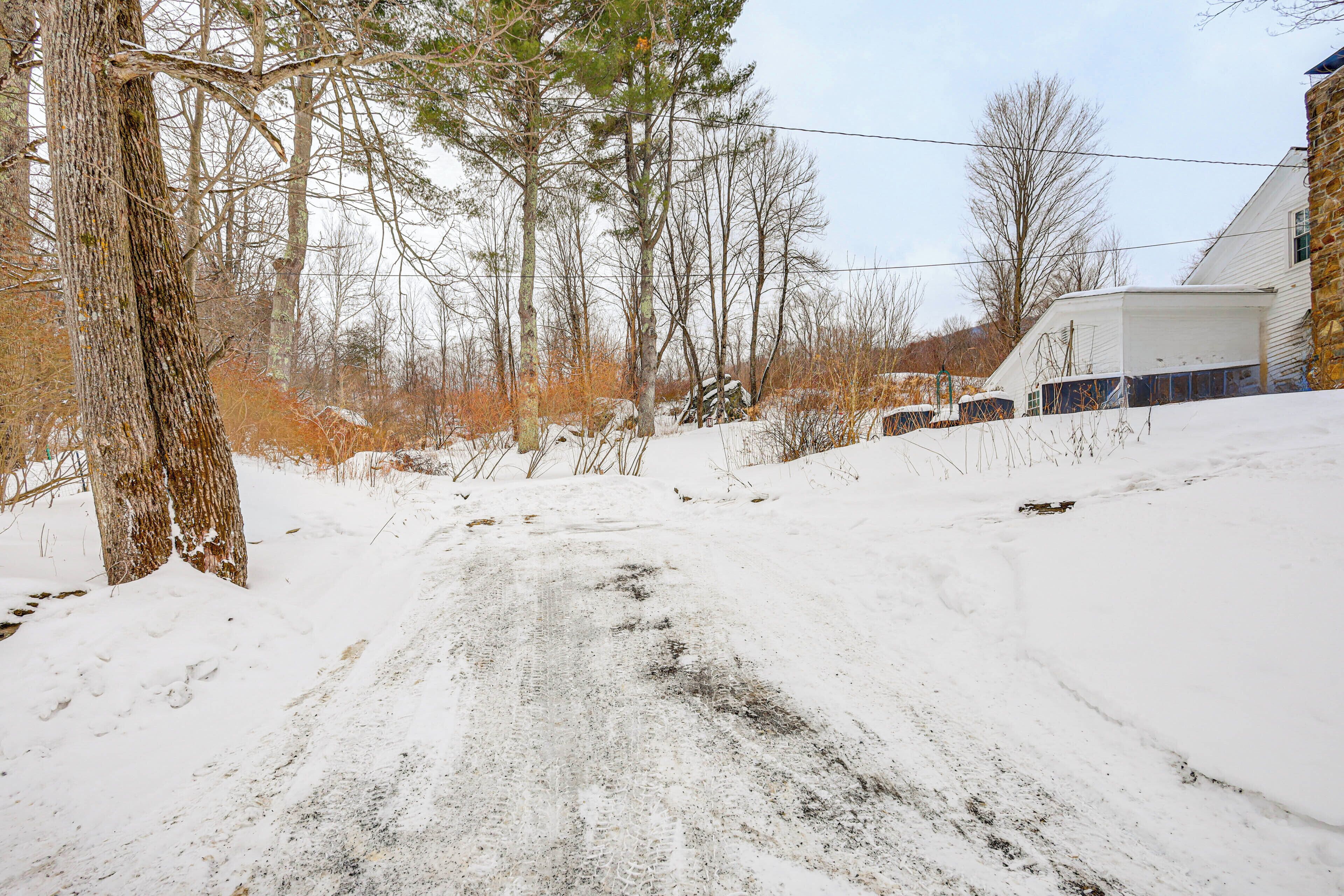 A snow-covered rural road with a stone house on the right.