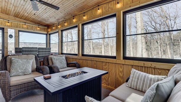 A cozy room with wicker furniture, large windows, and a ceiling fan. - Peaceful Nature Retreat w/ Hot Tub in Eastern WV! (Lost River)