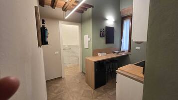 Una cocina compacta con cubierta de madera, lavavajillas integrado y una pequeña zona de bar.