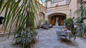Une cour avec des sièges en plein air, des plantes en pot et une statue.