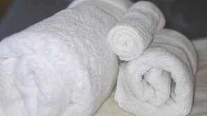 Uma cama com toalhas brancas bem dobradas e um travesseiro com a palavra 'Dream' visível.