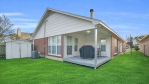 Une maison de plain-pied dotée d’un patio couvert, d’une façade en briques et d’une pelouse bien entretenue.