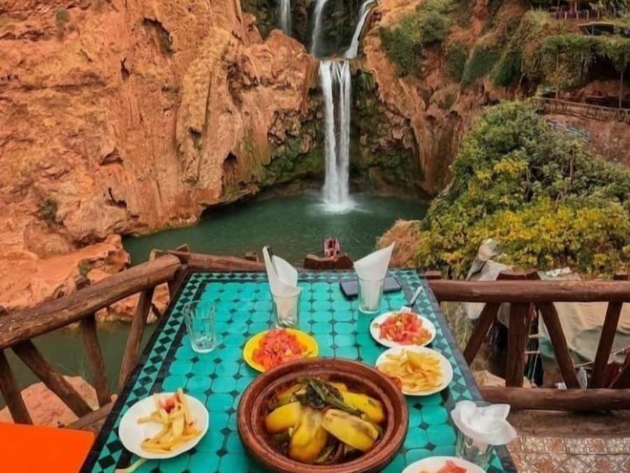 Mesa dispuesta con diferentes platos y vista a una cascada.
