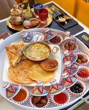 Un petit-déjeuner marocain traditionnel composé de viennoiseries, de confitures et de thé.