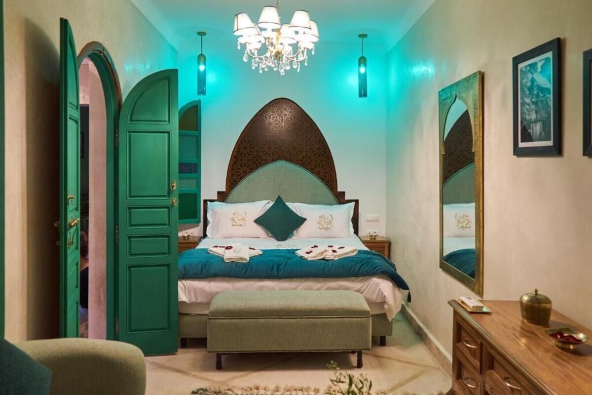 Une chambre à coucher avec un lit, un banc, une commode et un miroir.