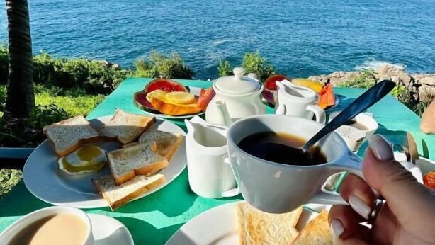 A table set with breakfast items including toast, butter, and coffee, overlooking a body of water. - Perfect view mirissa (Mirissa)