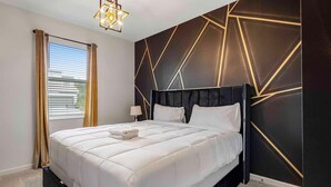 A modern bedroom with a large bed, a geometric wall design, and a window with curtains. - NBA Dream Mansion 15br Luxury Villa w Pool (Kissimmee)