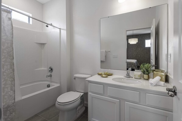 Une salle de bain moderne équipée d’une baignoire, de toilettes et d’un meuble-lavabo avec un miroir.