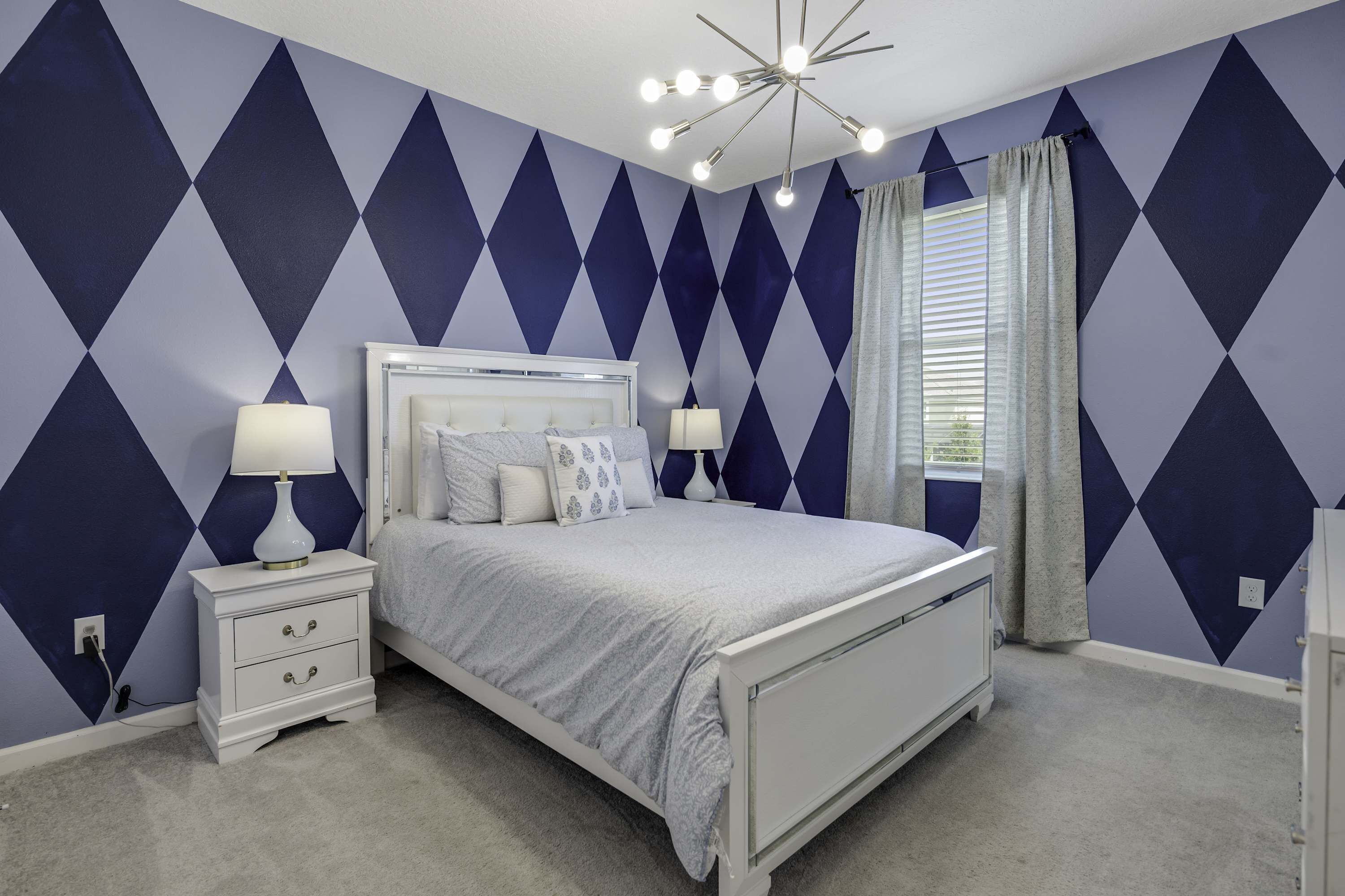 A bedroom with a bed, nightstands, and a modern ceiling light fixture.