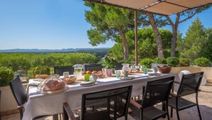 An outdoor dining area with a table set for four, overlooking a scenic landscape. - Mas Noves - Horizon Alpilles Villa (Noves)