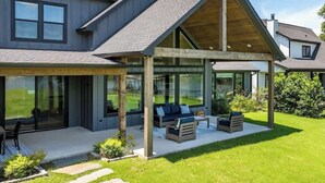 Una casa moderna con un porche cubierto, ventanas amplias y un césped bien cuidado.