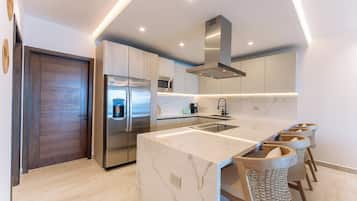 A modern kitchen with a marble island, stainless steel appliances, and bar stools.