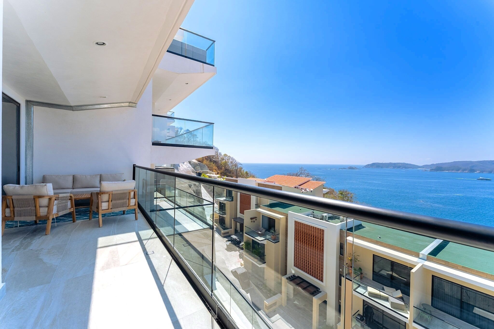 A modern balcony with glass railings overlooking a coastal view.