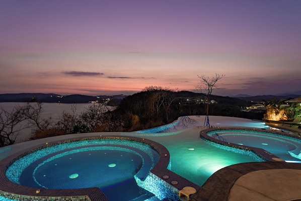 A pool area with a view of the water body and distant hills.