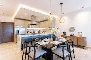 Een moderne keuken met een centraal eiland, roestvrijstalen apparatuur en hanglampen.