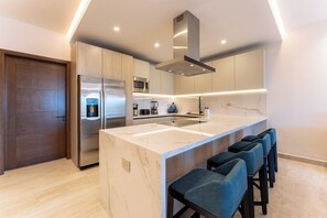 A modern kitchen with a large island, stainless steel appliances, and bar stools. - 2B Beach View | Shared Pool & Beach Access (Huatulco)