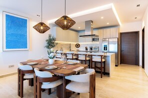 A modern kitchen with a central island, white cabinets, and stainless steel appliances. - 2BR Paradise Cove | Elevated Beach & Pool Views (Huatulco)