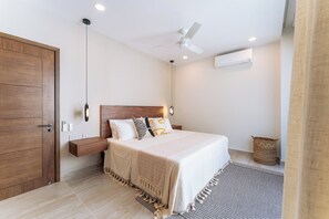 A bedroom with a bed, wooden wardrobe, ceiling fan, and a wall-mounted air conditioner. - 2BR Paradise Cove | Elevated Beach & Pool Views (Huatulco)