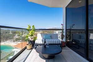 A balcony with a sofa, a table, and potted plants. - 2BR Paradise Cove | Elevated Beach & Pool Views (Huatulco)