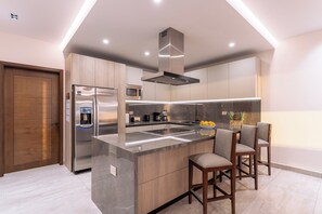 Una cocina moderna con una isla central, electrodomésticos de acero inoxidable y armarios de madera.