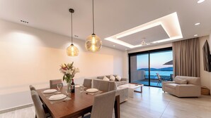 Ein stilvoller Essbereich mit einem Holztisch für zwei Personen, einer Couch und Blick auf das Meer.
