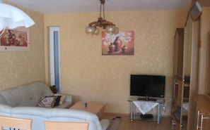 Una sala de estar con un sofá, televisión y un cuadro en la pared.