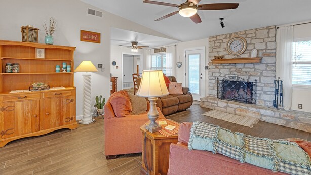 A cozy living room with a fireplace, a ceiling fan, and a wooden cabinet. - Dean's Retreat At Georgetown 3 Bedroom Home (Georgetown)