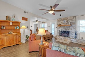A cozy living room with a fireplace, a ceiling fan, and a wooden cabinet. - Dean's Retreat At Georgetown 3 Bedroom Home (Georgetown)