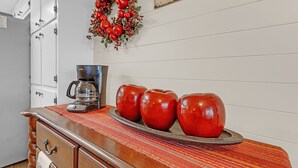 A kitchen counter with a coffee maker, a decorative plate with red apples, and a festive wreath. - Dean's Retreat At Georgetown 3 Bedroom Home (Georgetown)