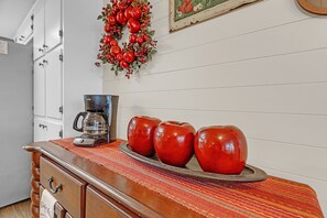 A kitchen counter with a coffee maker, a decorative plate with red apples, and a festive wreath. - Dean's Retreat At Georgetown 3 Bedroom Home (Georgetown)