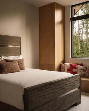 Ein Schlafzimmer mit einem Bett, einem Kleiderschrank und einem Fenster mit Blick auf Bäume.