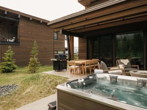 A modern outdoor patio with a hot tub, wooden furniture, and a grill. - 8 Speedwell 4 Bedroom Home (Big Sky)
