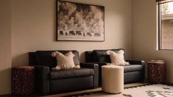 A living room with a sofa set, a rug, and a painting on the wall.