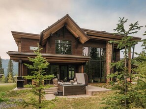 A modern two-story house with a large deck, outdoor seating, and a hot tub. - 8 Speedwell 4 Bedroom Home (Big Sky)