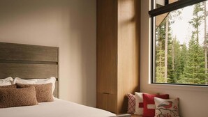 A bedroom with a bed, a window with a view of trees, and a wooden headboard. - 8 Speedwell 4 Bedroom Home (Big Sky)