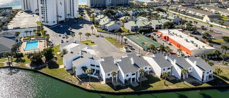 An aerial view of a coastal hotel complex with multiple buildings, a swimming pool, and a marina.