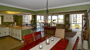 A spacious living area with a dining table, chairs, a sofa, and a kitchen in the background. - Shoreline Towers 1046 3 Bedroom Condo (Destin)