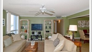 A living room with a ceiling fan, a television, and two sofas. - Shoreline Towers 1046 3 Bedroom Condo (Destin)