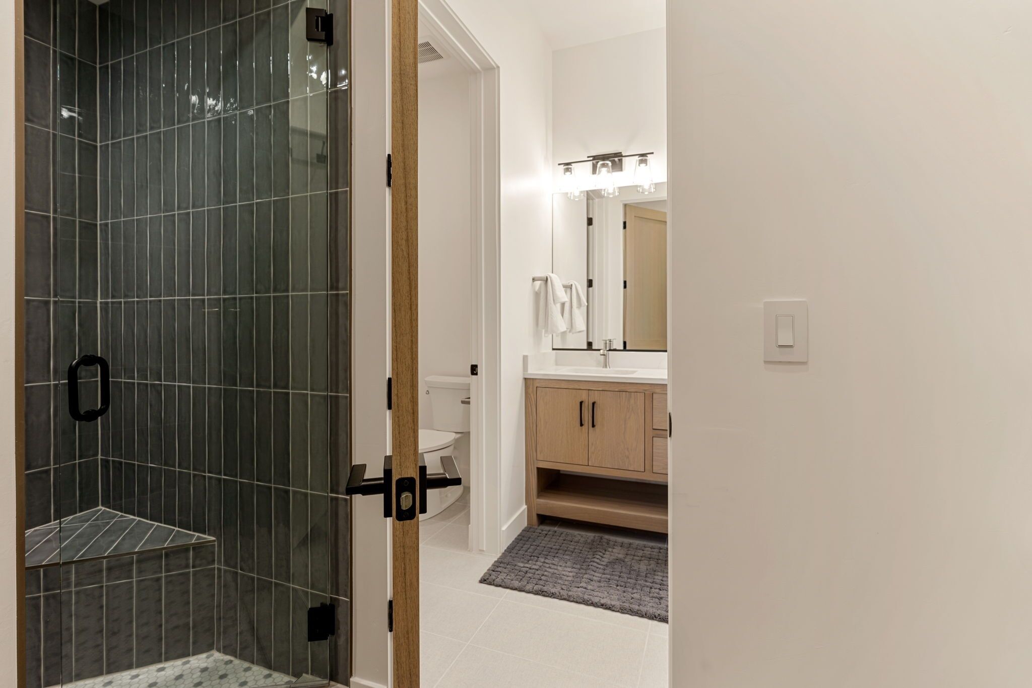 Une salle de bain moderne avec une douche à parois de verre, des toilettes, un lavabo avec un miroir et des meubles en bois.