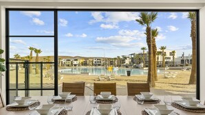 A dining table set for six with a view of a pool and beach. - Pearl Beach B 3 Bedroom Townhouse (St. George)