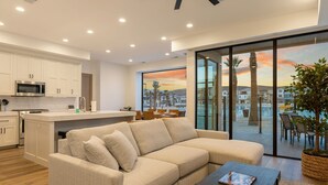 A modern living area with a sofa, coffee table, and a view of a cityscape through large windows. - Pearl Beach A 3 Bedroom Townhouse (St. George)
