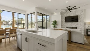 A modern kitchen with a large island, a built-in TV, and a stone backsplash. - Pearl Beach A 3 Bedroom Townhouse (St. George)
