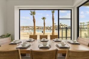 A dining area with a view of a pool and palm trees. - The Ultimate Pearl Beach Experience 9 Bedroom Home (St. George)