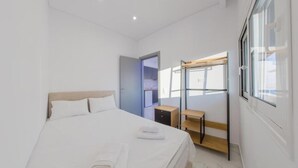 Ein modernes Schlafzimmer mit einem Bett, einem Nachttisch aus Holz, einem kleinen Tisch und einem Kleiderschrank.