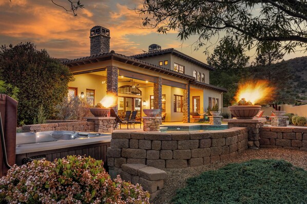 A two-story house with a stone exterior, a swimming pool, and outdoor seating.