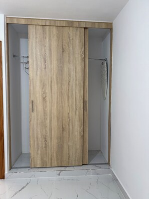 Ein Zimmer mit Holzschrank, Metallvorhangstange und Fliesenboden.
