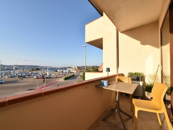 A balcony with a table and chair, a view of a marina, and a clear sky. - Charming Accommodation in Palau (Palau)